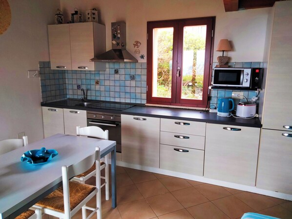 A kitchen with a tiled backsplash, a microwave, a toaster, and a window with a view of greenery. - Wonderful view of the sea. Romantic and relaxing place suitable for a couple. (Sassari)