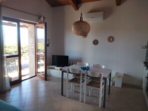 A dining area with a table and chairs, a television on a stand, and an air conditioning unit on the wall. - Wonderful view of the sea. Romantic and relaxing place suitable for a couple. (Sassari)
