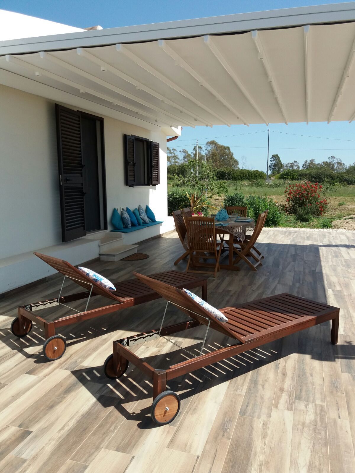 Un patio con dos sillones de madera con ruedas, una mesa y sillas.