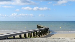 A wooden pier extending into calm waters with a clear sky above.