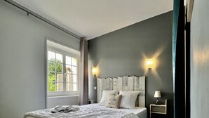 A modern bedroom with a large bed, a nightstand, and a wall-mounted lamp.