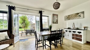 A spacious kitchen with a dining area, large windows, and a view of the garden.