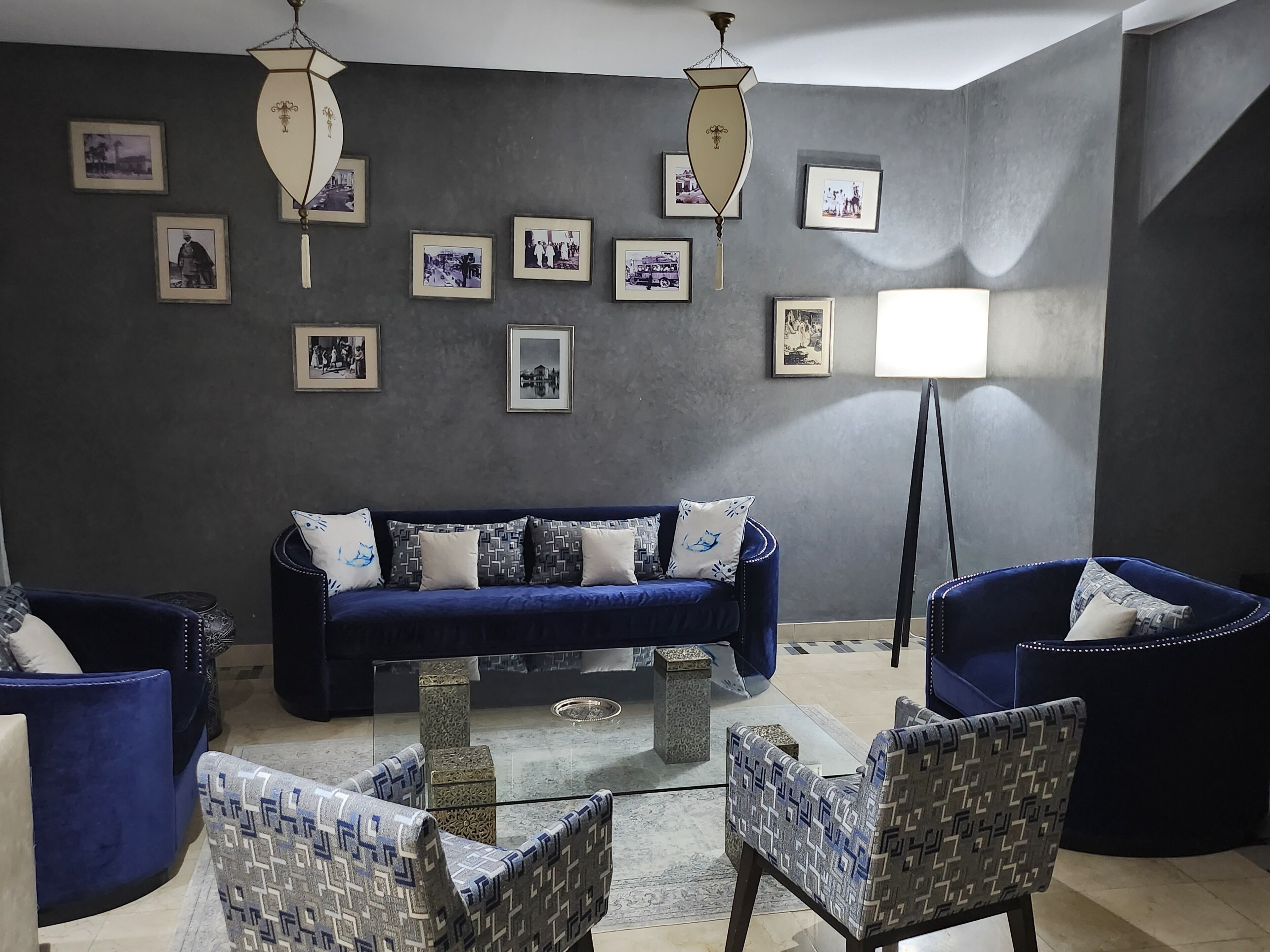 Un salon moderne avec un canapé bleu foncé, des fauteuils à motifs et une table basse en verre.