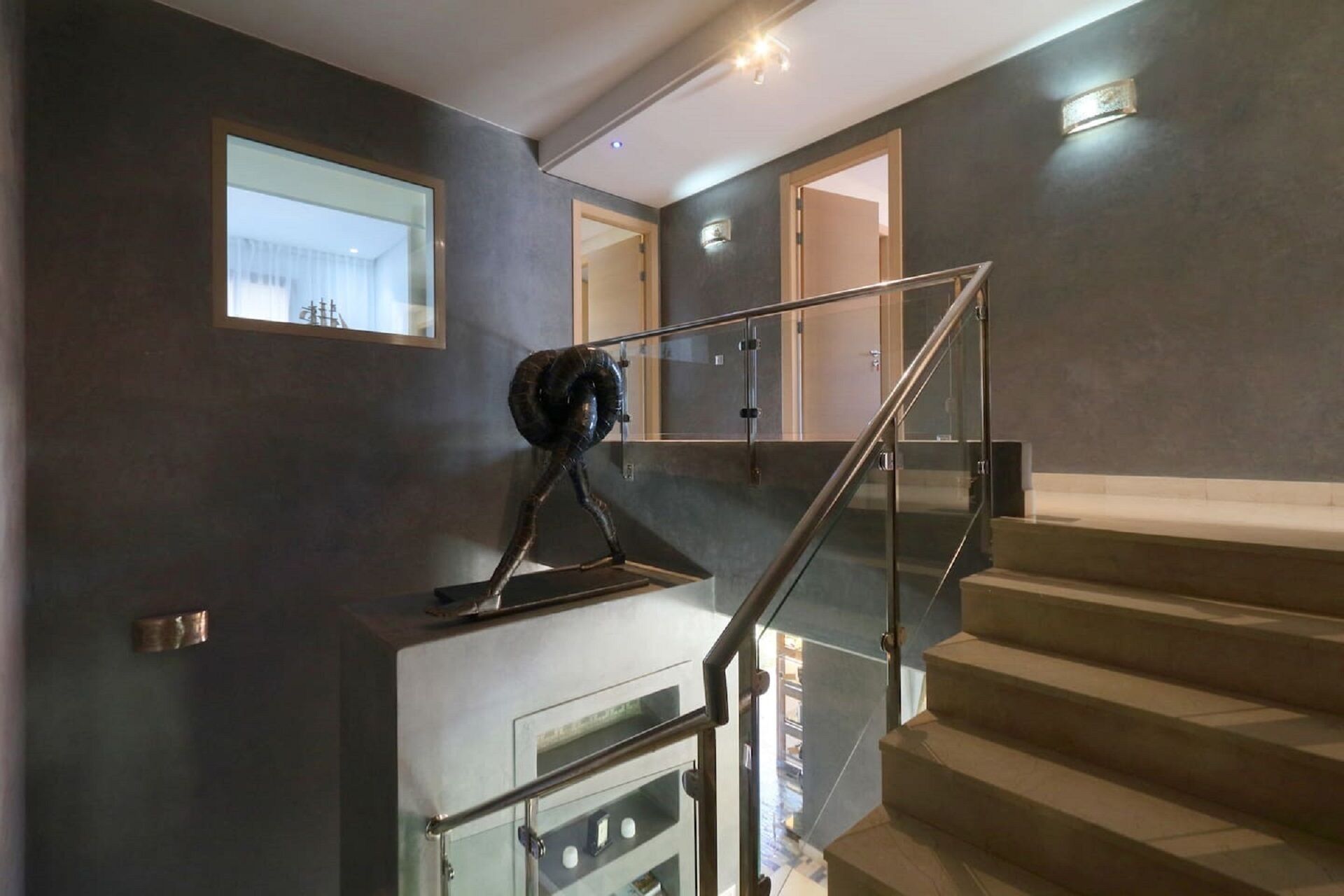 A modern staircase with glass railings and a dark wall.