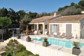 A poolside area with a pool, lounge chairs, and a dining setup.