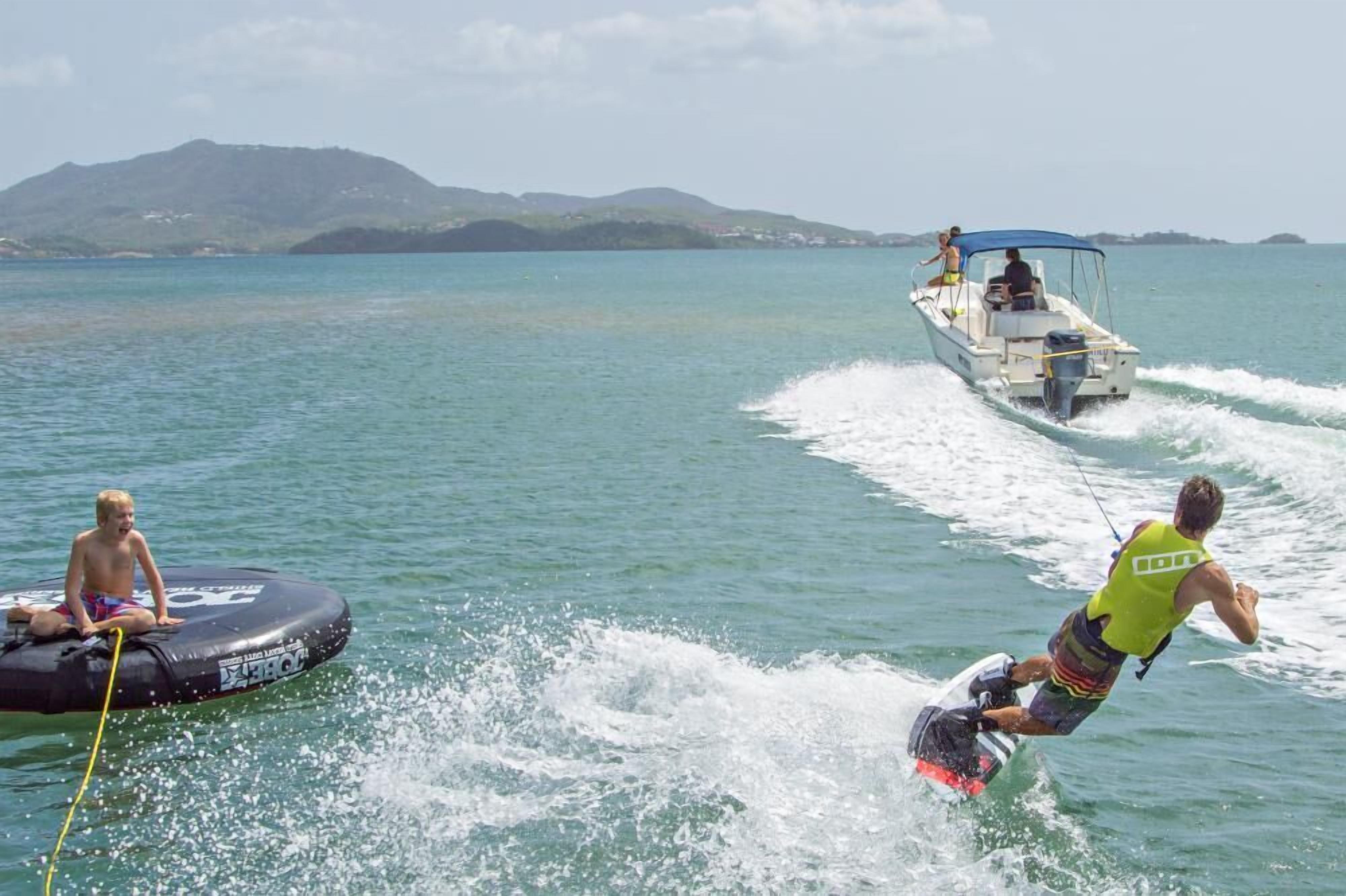 A wakeboarding scene with a boat and a person wakeboarding.