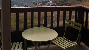 A balcony with a table and chairs, overlooking a mountainous landscape during sunset. - T3 for 6/7 people with direct access to the slopes, beautiful view, summer swimming pool, shops (Valmeinier)