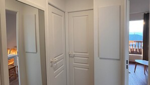 A hallway with wooden flooring, white walls, and doors leading to different rooms. - T3 for 6/7 people with direct access to the slopes, beautiful view, summer swimming pool, shops (Valmeinier)