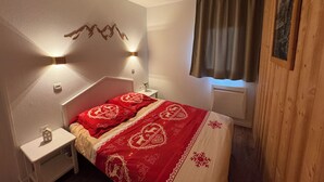 A bedroom with a bed, bedside tables, wall-mounted lights, a window with curtains, and a framed picture on the wall. - T3 for 6/7 people with direct access to the slopes, beautiful view, summer swimming pool, shops (Valmeinier)