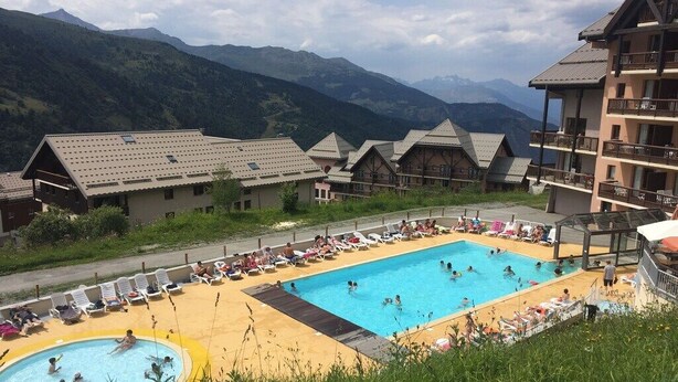 A resort with a swimming pool surrounded by lounge chairs and a mountain backdrop. - T3 for 6/7 people with direct access to the slopes, beautiful view, summer swimming pool, shops (Valmeinier)