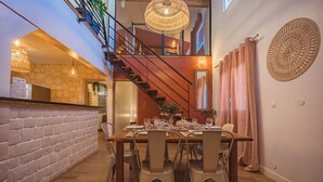 A dining area with a wooden table set for six, a staircase, and a decorative wall piece. - Villa Noja***** HEATED POOL, beaches, volcano, hiking, Trail... (Saint Louis)