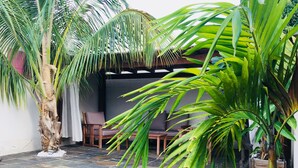 A patio area with a tiled floor, a wooden chair, and a thatched roof structure. - Villa Noja***** HEATED POOL, beaches, volcano, hiking, Trail... (Saint Louis)