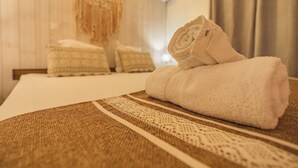 A neatly made bed with a rolled white towel, a patterned throw, and a wall-mounted air conditioner. - Villa Noja***** HEATED POOL, beaches, volcano, hiking, Trail... (Saint Louis)