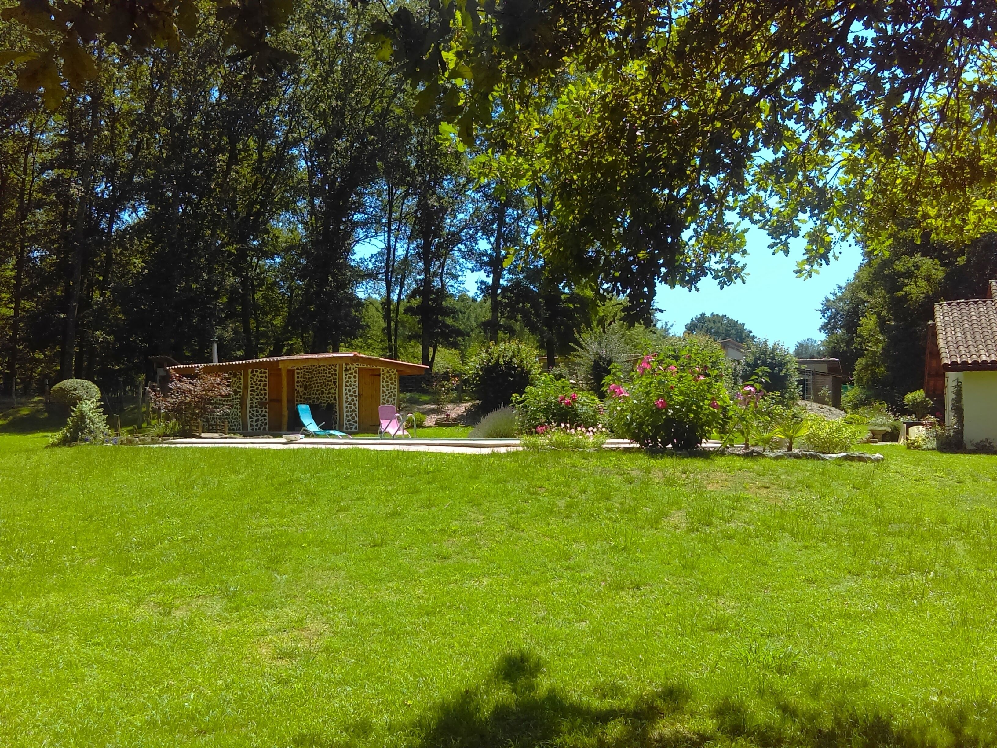 A well-maintained garden with a small gazebo, a pool, and a lawn.