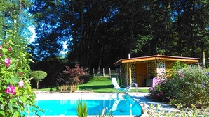 Piscina rodeada de vegetación exuberante y un pequeño pabellón.