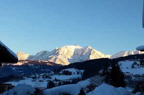 Un paysage de montagne avec des sommets enneigés et un village en contrebas.