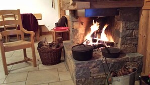 A cozy room with a stone fireplace, a wooden chair, a wicker basket, and a metal bucket.