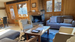 A cozy living room with a stone fireplace, wooden furniture, and a cowhide rug.