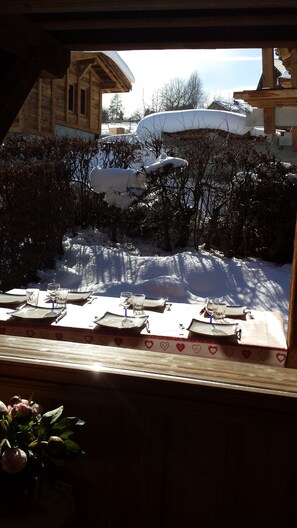 Une table à manger installée à l’extérieur, dans un décor enneigé.