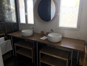 Bathroom features a double vanity with two vessel sinks and a round mirror.
