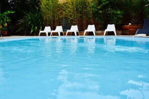 Relax by the serene pool surrounded by lush greenery and comfortable lounge chairs.