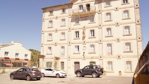 A multi-story building with a classical architectural style, featuring a balcony with a statue, multiple windows, and a sign reading "MINOTERIE S JEAN". - The bright and colorful Duplex Mill in Saint-Rémy-de-Provence (Saint-Rémy-De-Provence)