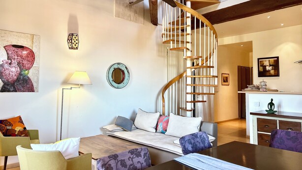 A modern living room with a spiral staircase, a sofa set, a dining table, and a kitchen area. - The bright and colorful Duplex Mill in Saint-Rémy-de-Provence (Saint-Rémy-De-Provence)