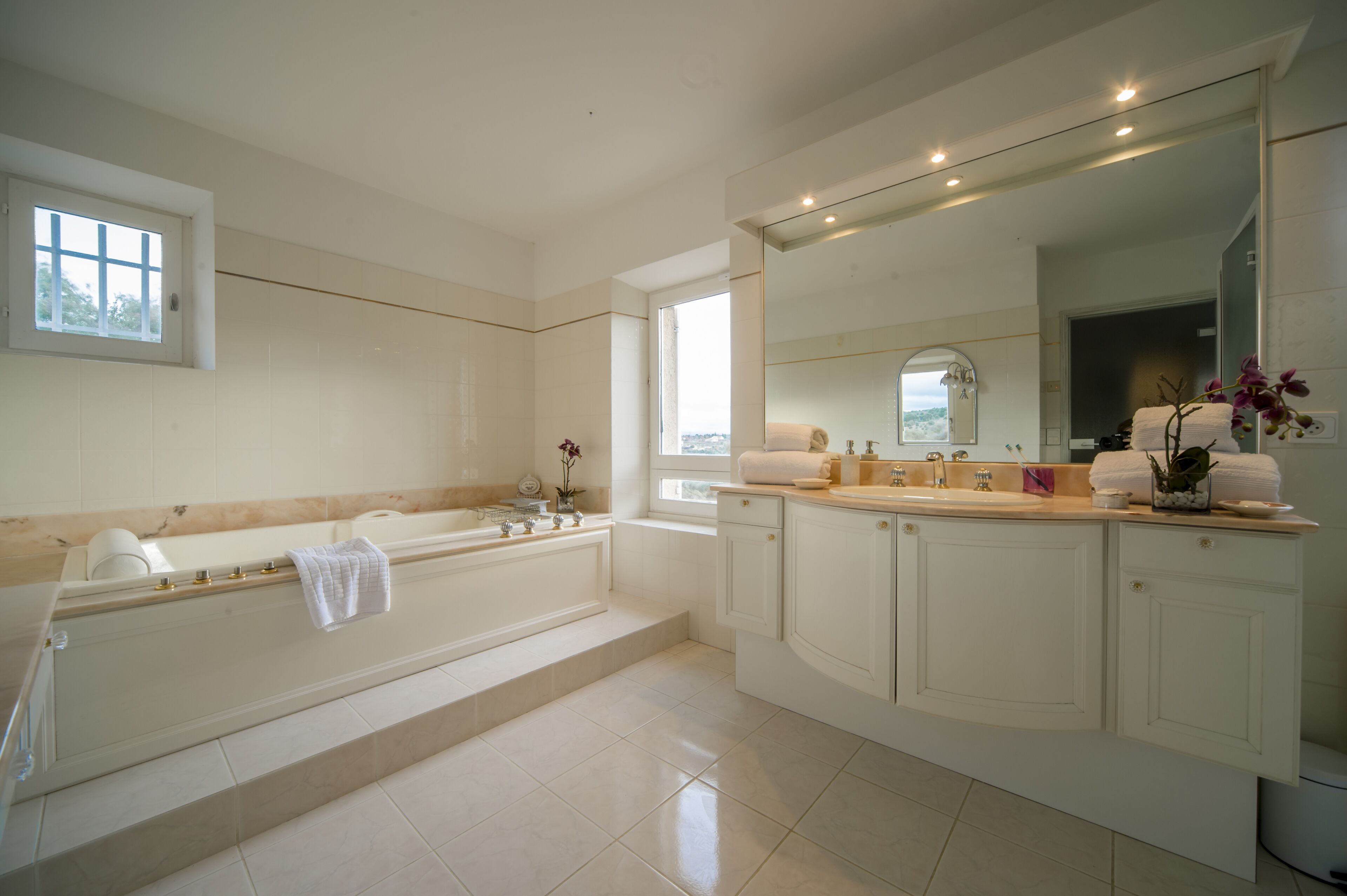 A modern bathroom with a large bathtub, a separate shower area, and a vanity with a mirror.