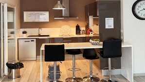 Una cocina moderna con una isla central, taburetes de bar y un reloj en la pared.