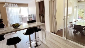 Una cocina moderna con zona de comedor, que cuenta con un ventanal grande, una mesa y taburetes de bar.