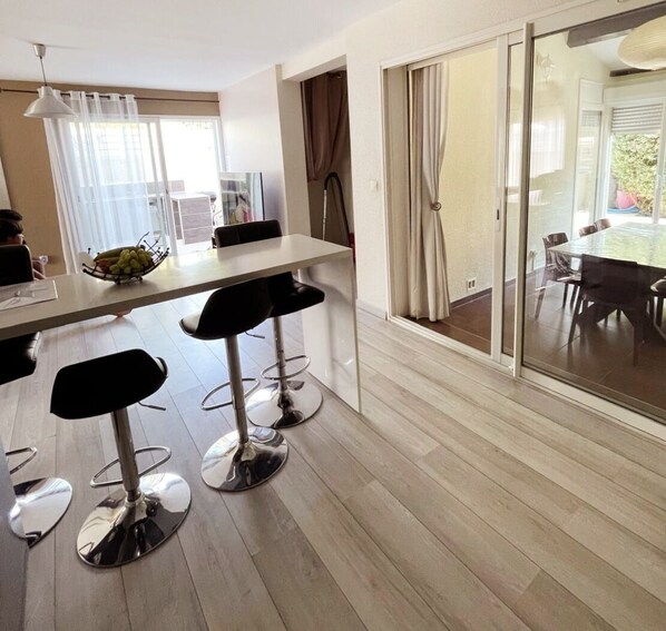 Una cocina moderna con zona de comedor, que cuenta con un ventanal grande, una mesa y taburetes de bar.