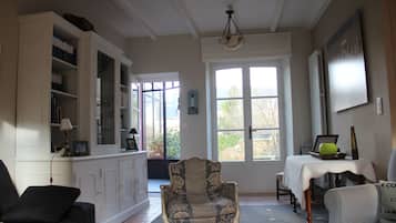 A living room with a sofa, armchair, and a dining table with a lamp.