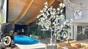 Ein modernes Interieur mit Schwimmbad, Holzboden und einer gemütlichen Sitzecke mit Kissen.