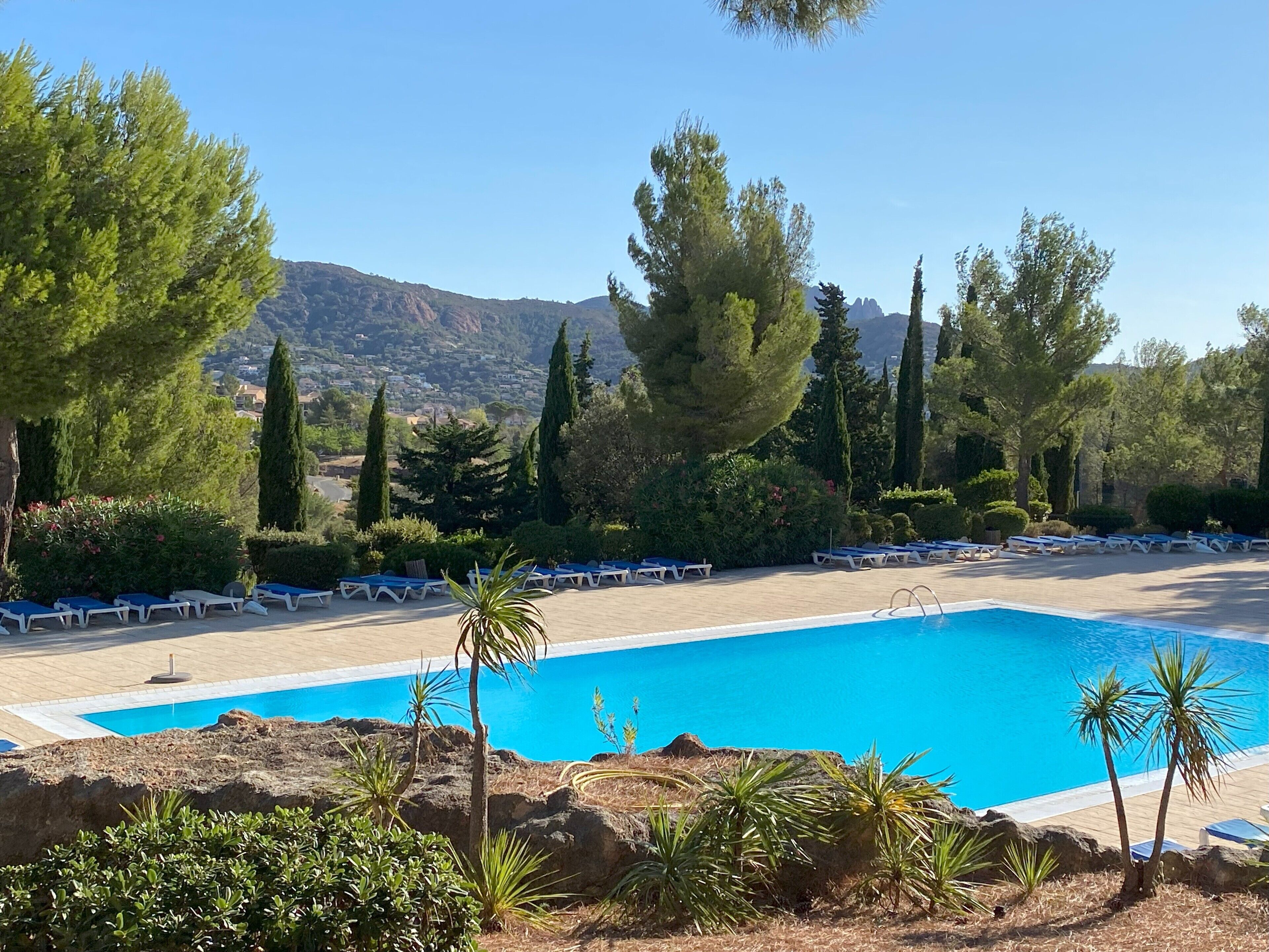 Un espace piscine doté de chaises longues et offrant une vue sur un paysage montagneux.