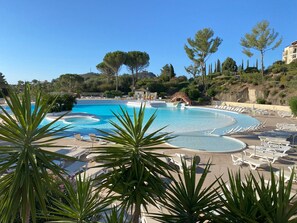 Une grande piscine extérieure dotée de nombreux transats et agrémentée d’une petite cascade.