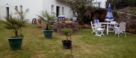 A garden with potted plants, a stone wall, and outdoor furniture.