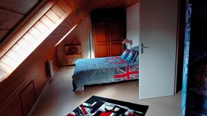 Un dormitorio con techo inclinado, una cama con cubierta a cuadros del Union Jack, un armario y un radiador.