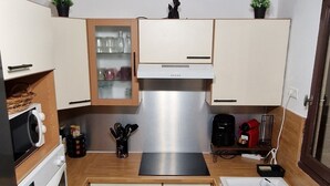 Una cocina compacta con armarios de madera, estufa de acero inoxidable, microondas y pileta.