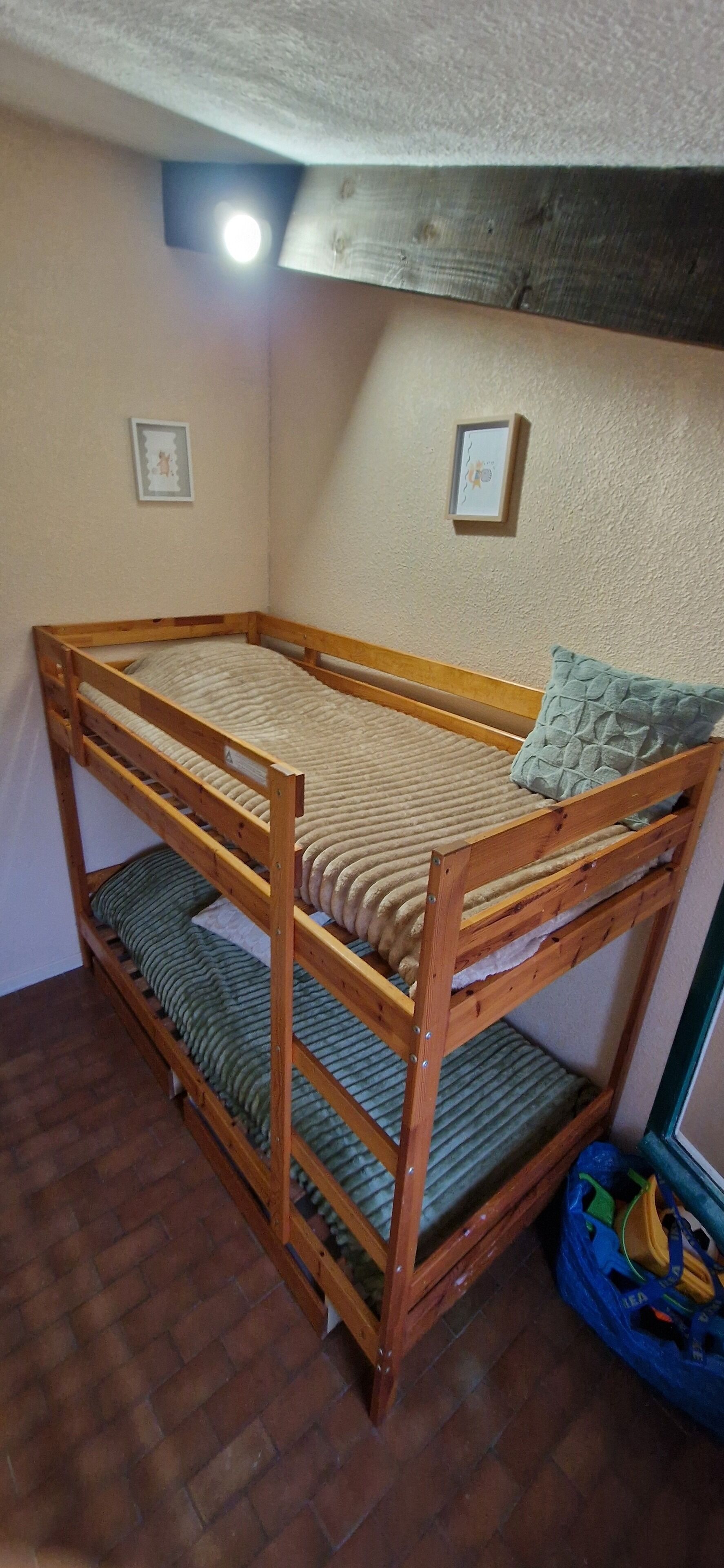 A bunk bed with a wooden frame and two levels of sleeping space, each with a mattress and pillow.