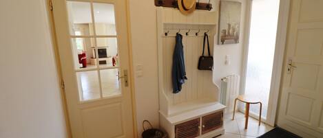 A hallway with a bench, a coat rack, and a door leading to a room.