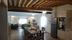 Una cocina amplia con vigas de madera, una mesa de comedor con sillas, un refrigerador y un microondas.