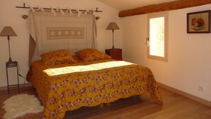 Un dormitorio con una cama, dos lámparas de noche, una ventana y un cuadro en la pared.