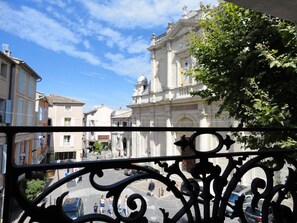 Une vue d’une rue bordée d’immeubles, avec notamment une église imposante dotée d’un clocher abritant une horloge.