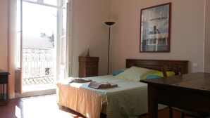 A bedroom with a bed, a nightstand, a desk, and a poster on the wall.