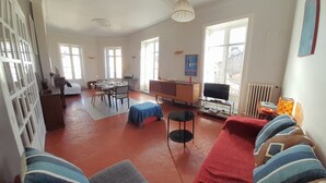 A spacious living area with a dining table, sofa, and TV.