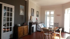 A dining area with a wooden table and chairs, a fireplace, and a view of the outside through a large window.