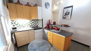 A compact kitchen with a small round table, a sink, and a stove.