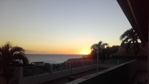 A balcony with a view of the sunset over the ocean. - F2 Panoramic view sea, mountain and swimming pool view of the residence (Le Carbet)