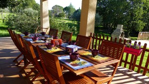 A wooden table set outdoors with chairs, surrounded by a wooden fence and greenery.
