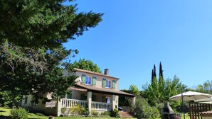 A two-story house with a stone wall in the front yard, a satellite dish, and a chimney.